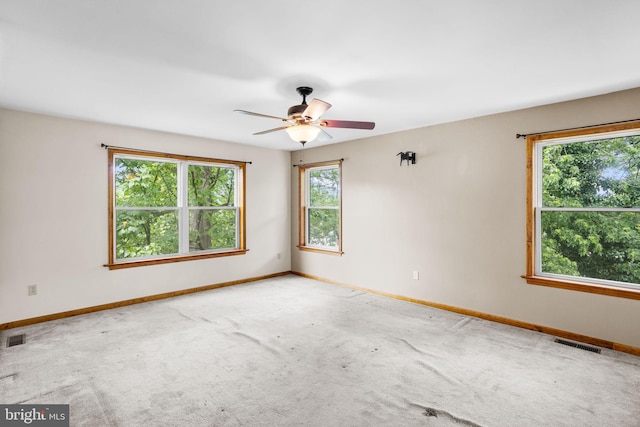 carpeted spare room with visible vents, a ceiling fan, and baseboards