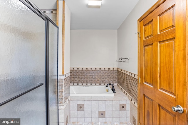 full bathroom featuring a bath, wainscoting, and a stall shower