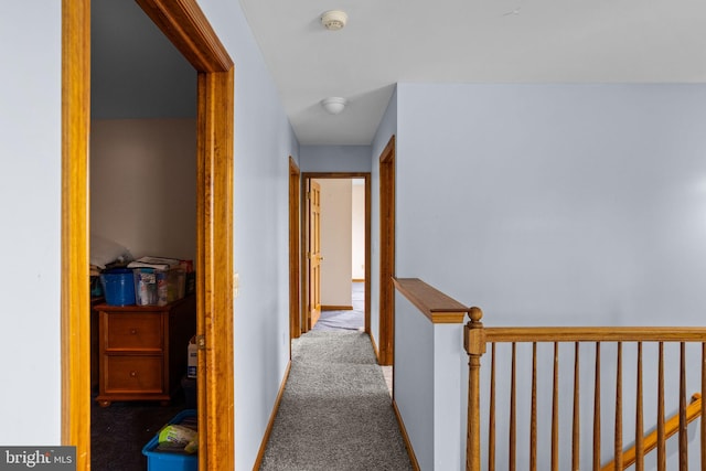 hall featuring carpet flooring and an upstairs landing
