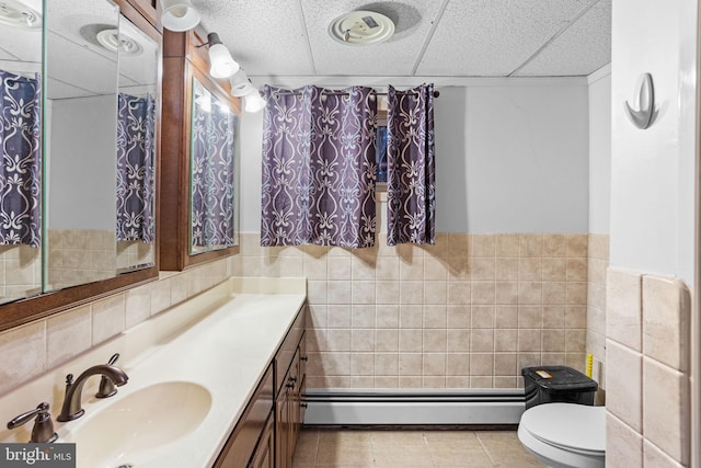 bathroom featuring tile patterned floors, toilet, vanity, tile walls, and baseboard heating