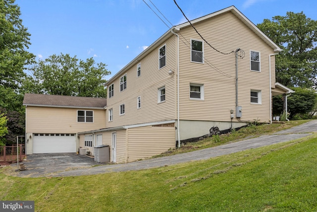 view of side of property with an attached garage, a lawn, and aphalt driveway