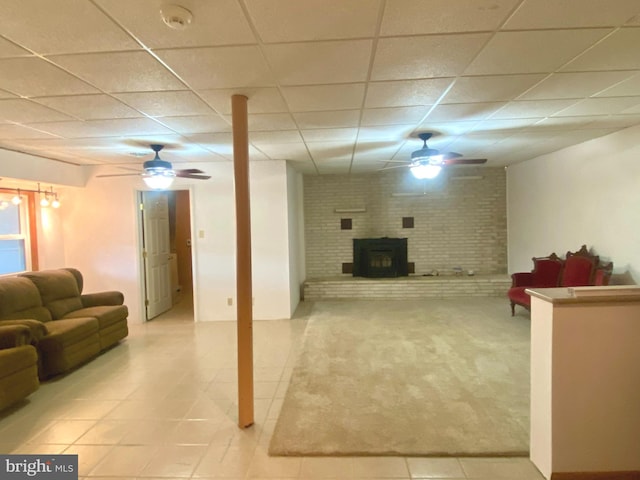 living area featuring baseboard heating, a wood stove, a drop ceiling, carpet floors, and ceiling fan