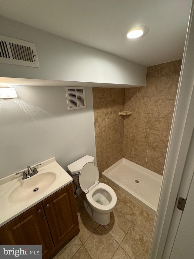 bathroom featuring vanity, tiled shower, tile patterned floors, and toilet