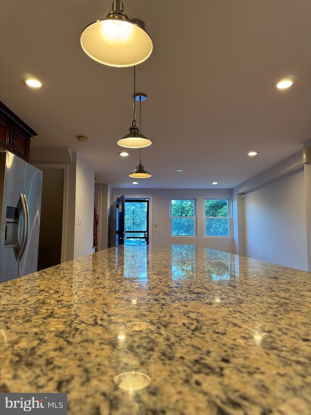 kitchen with pendant lighting, light stone countertops, and stainless steel fridge with ice dispenser