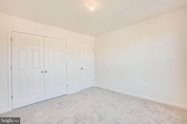 unfurnished bedroom with light colored carpet and a closet