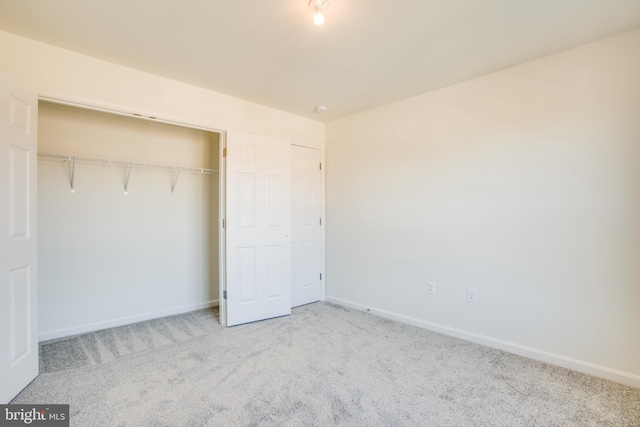 unfurnished bedroom with a closet and light colored carpet