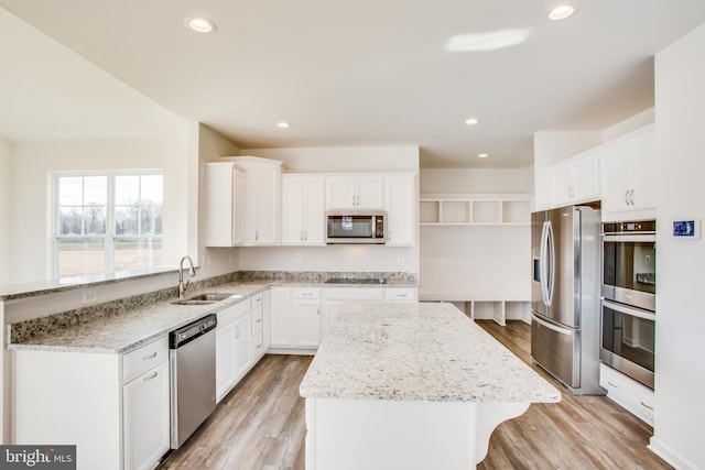 kitchen with light stone countertops, sink, light wood-type flooring, and appliances with stainless steel finishes