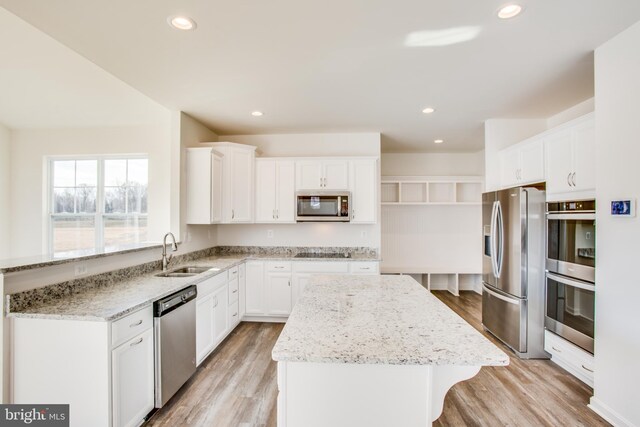 2107 Warrenton Rd, Fredericksburg, VA 22406 - kitchen with appliances with stainless steel finishes, a sink, a center island, light wood-style flooring, and light stone counters