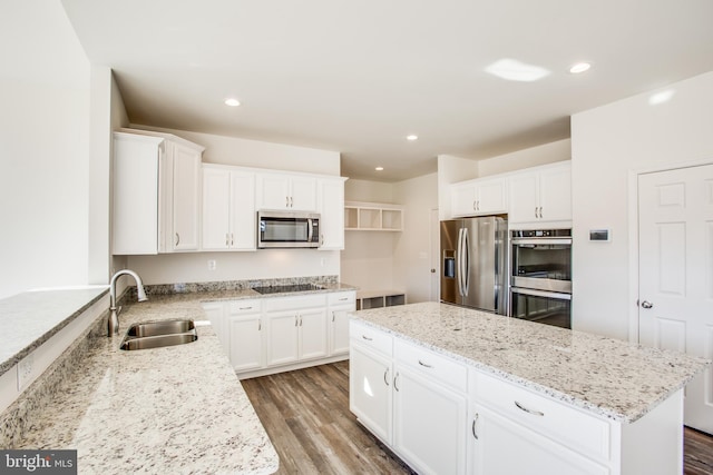 kitchen with hardwood / wood-style floors, sink, appliances with stainless steel finishes, light stone counters, and white cabinetry