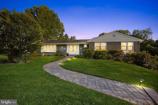 single story home with french doors and a lawn