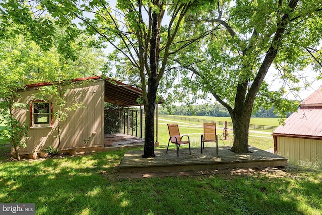 view of yard featuring a storage unit, a rural view, and a wooden deck