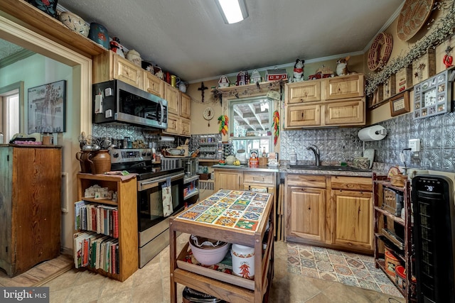 kitchen featuring sink, ornamental molding, tasteful backsplash, light tile patterned flooring, and stainless steel appliances