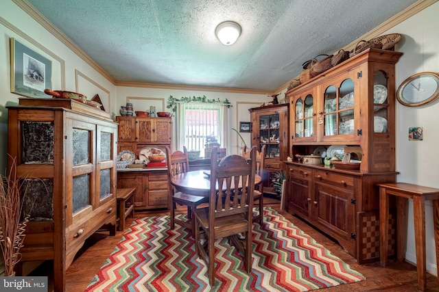 dining area with hardwood / wood-style flooring, crown molding, and a textured ceiling