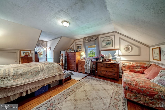 bedroom with hardwood / wood-style flooring, lofted ceiling, and a textured ceiling