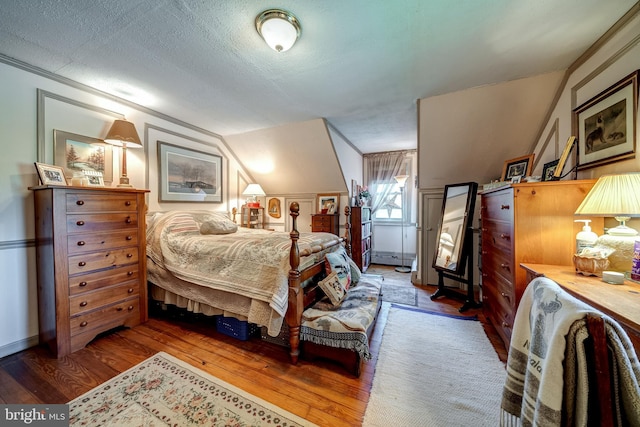 bedroom featuring a textured ceiling, hardwood / wood-style floors, and lofted ceiling