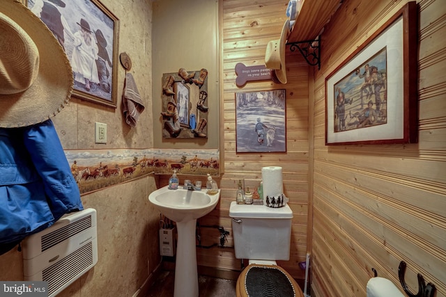 bathroom with heating unit, wood walls, and toilet