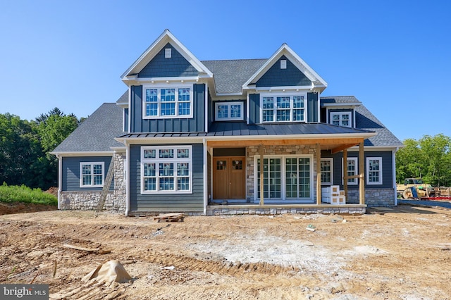 craftsman-style house featuring stone siding, covered porch, metal roof, and a standing seam roof