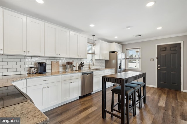 kitchen featuring dark wood-type flooring, stainless steel appliances, decorative light fixtures, white cabinets, and ornamental molding