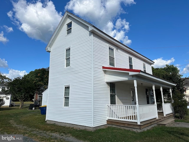 view of side of property with covered porch and a yard