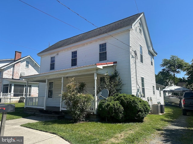 view of front of home featuring central AC unit, a porch, and a front yard