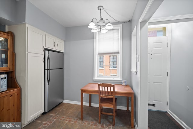 kitchen featuring a notable chandelier, white microwave, white cabinetry, and stainless steel refrigerator