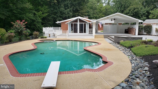 view of pool featuring ceiling fan, a diving board, and a patio area