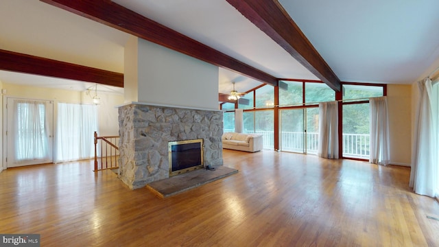 unfurnished living room featuring light wood-type flooring, ceiling fan, lofted ceiling with beams, and a stone fireplace