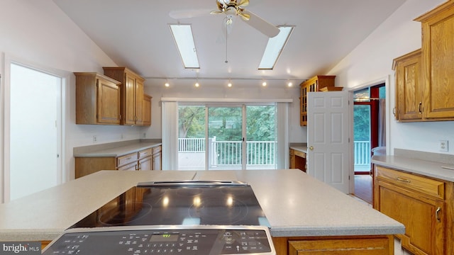 kitchen with black range, vaulted ceiling with skylight, a center island, and ceiling fan