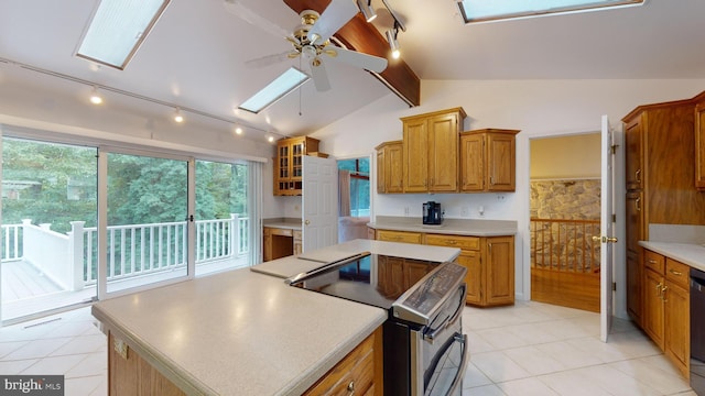 kitchen with vaulted ceiling with skylight, stainless steel electric stove, a center island, and ceiling fan