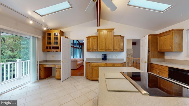 kitchen featuring black dishwasher, ceiling fan, light tile patterned floors, and lofted ceiling with skylight