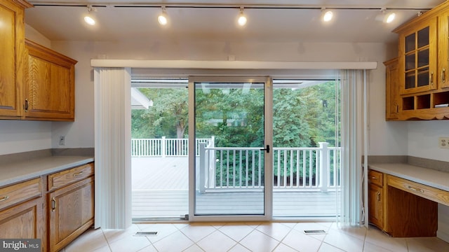 doorway to outside featuring plenty of natural light, rail lighting, and light tile patterned flooring