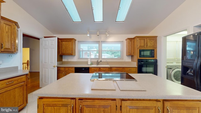 kitchen with black appliances, a center island, washer / dryer, and lofted ceiling with skylight