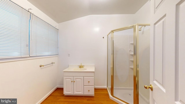 bathroom with a shower with door, vanity, vaulted ceiling, and hardwood / wood-style floors