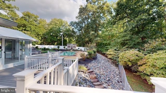 deck featuring a fenced in pool and a storage shed