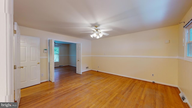 empty room featuring a healthy amount of sunlight, ceiling fan, and light hardwood / wood-style floors