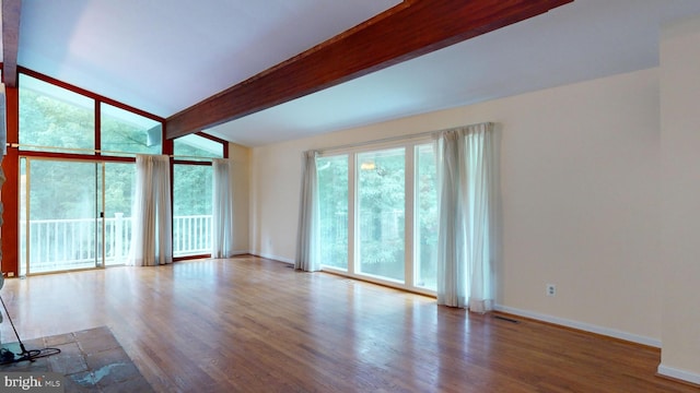 empty room with a healthy amount of sunlight, light wood-type flooring, and lofted ceiling with beams