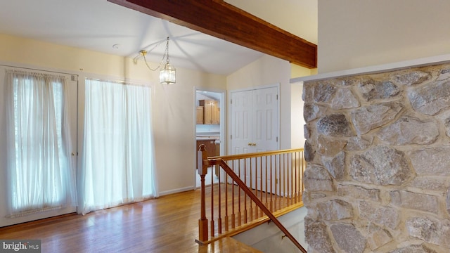 corridor with hardwood / wood-style floors, a chandelier, and vaulted ceiling with beams