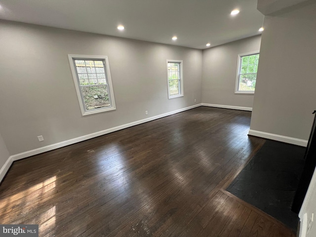 empty room with a healthy amount of sunlight and dark wood-type flooring