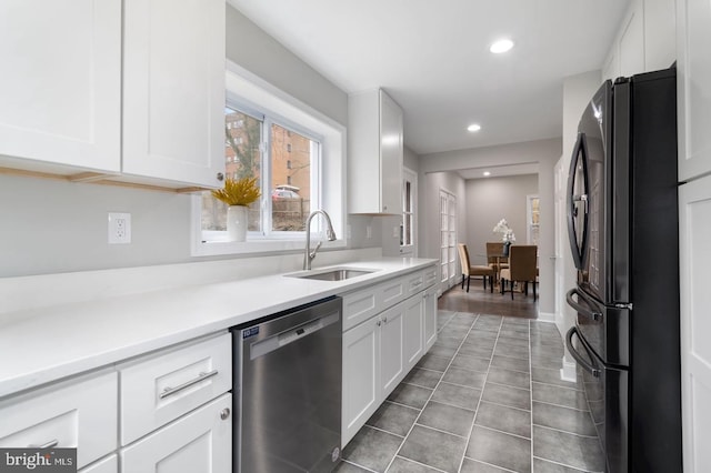 kitchen with black fridge, stainless steel dishwasher, sink, white cabinets, and light hardwood / wood-style floors