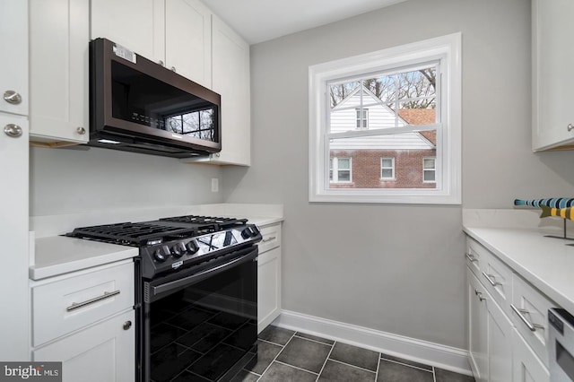 kitchen featuring white cabinets, black gas range oven, and dark tile patterned flooring