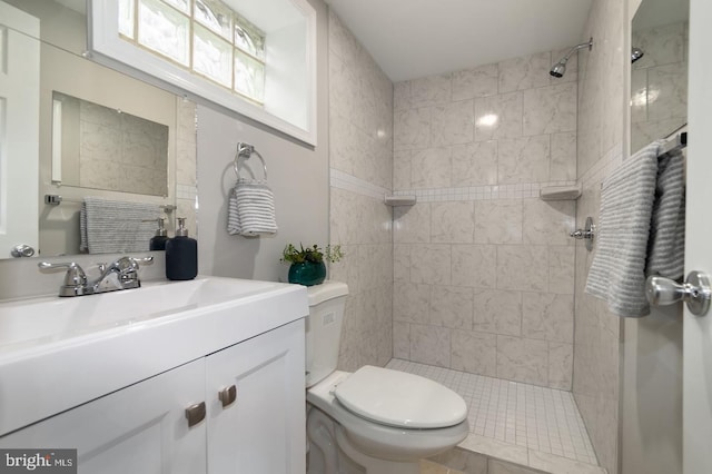 bathroom with a tile shower, vanity, and toilet