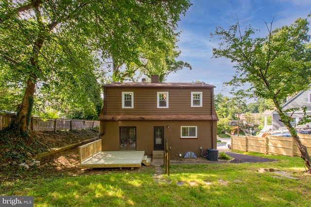 rear view of property with cooling unit, a deck, and a yard