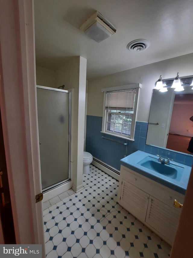 bathroom featuring walk in shower, vanity, baseboard heating, tile walls, and toilet