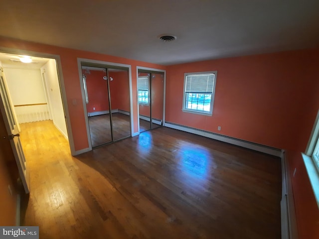 unfurnished bedroom with wood-type flooring and two closets