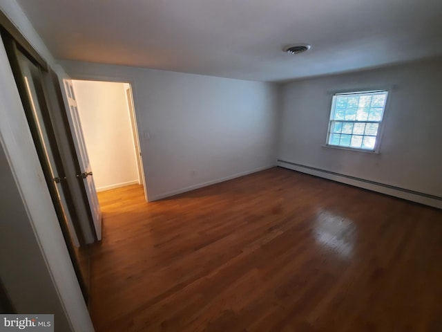 spare room featuring dark hardwood / wood-style floors and baseboard heating