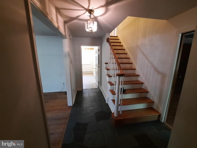 stairs with baseboard heating and a notable chandelier