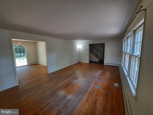 unfurnished room with a chandelier, wood-type flooring, and a baseboard radiator