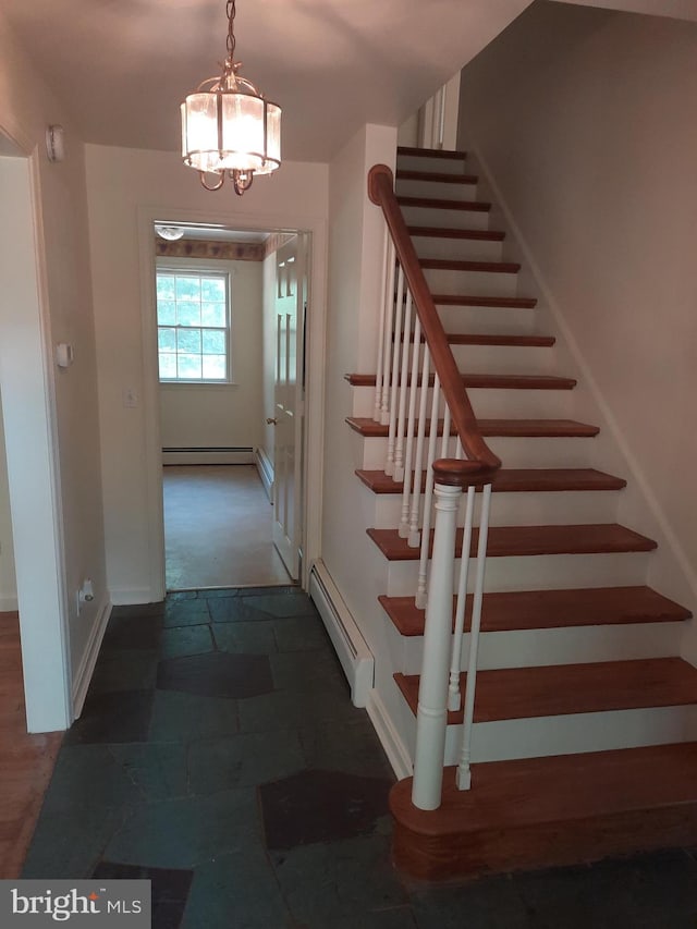 stairway with a notable chandelier and a baseboard heating unit