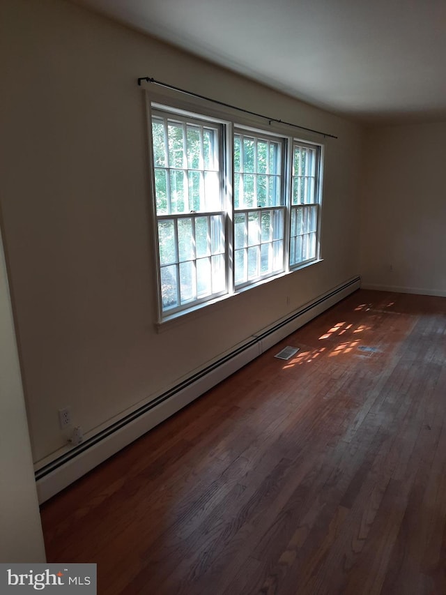 spare room featuring a baseboard radiator and dark wood-type flooring