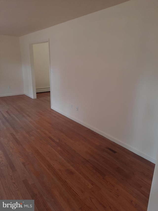 empty room featuring hardwood / wood-style floors and a baseboard radiator